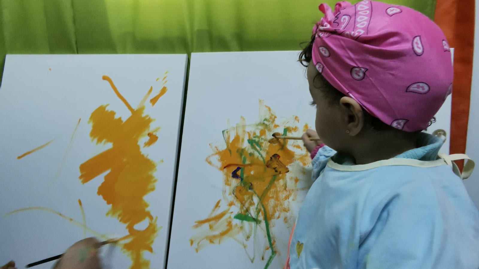 Child painting on canvas with colorful background.